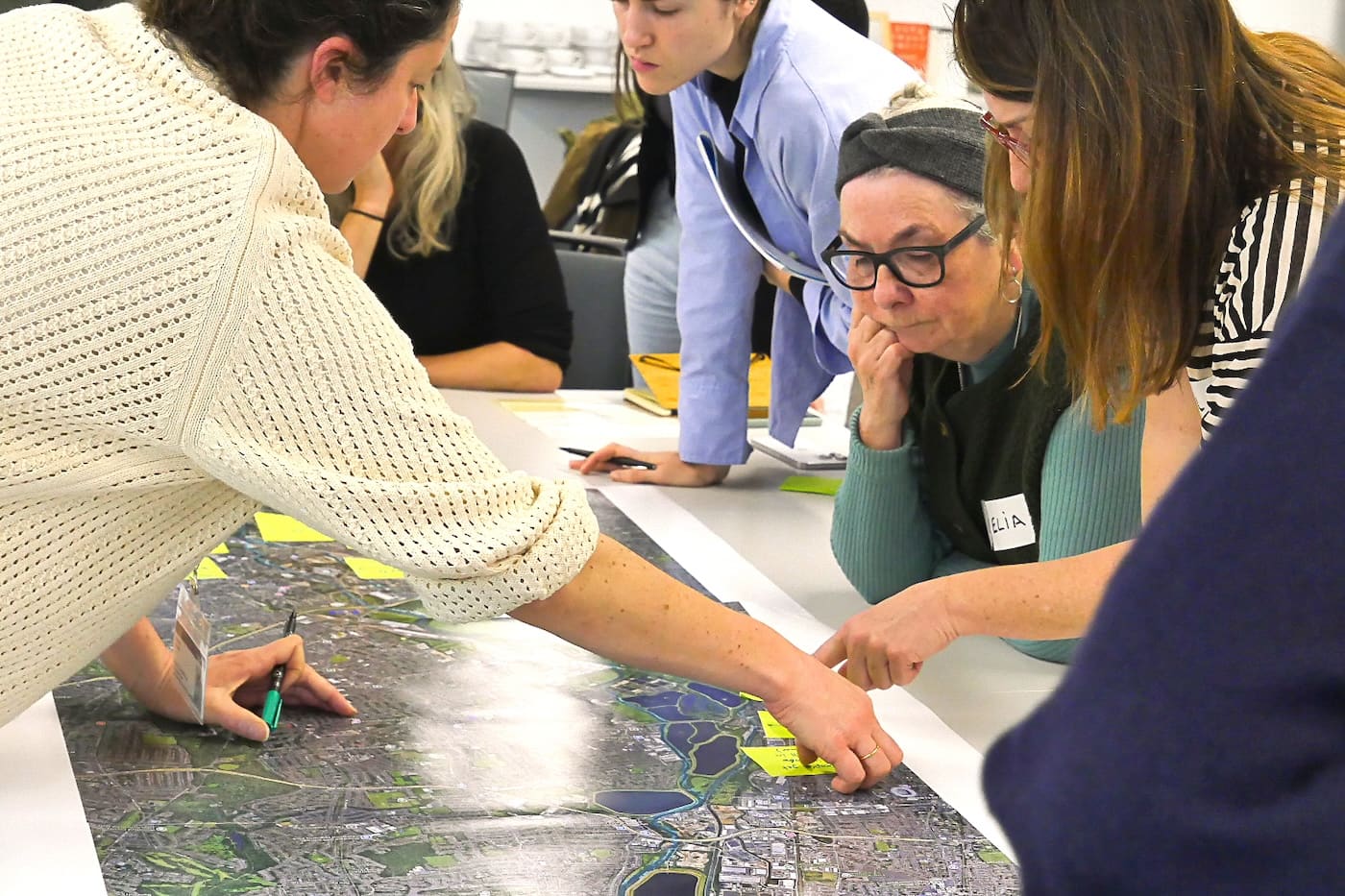 Participants lean in over the aerial map, pointing out places along the river and adding sticky notes